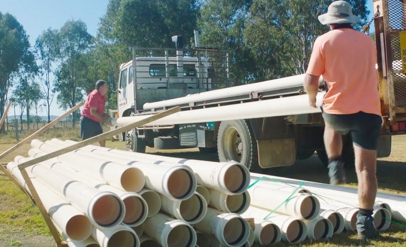 2 men loading Vinidex PVC pressure pipes in a truck.